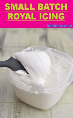 small batch royal icing in a plastic container with a black spoon on the side