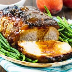 a plate with meat, green beans and an apple on the table next to it