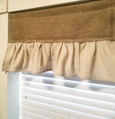 a close up of a window with a curtain on the side and blinds behind it