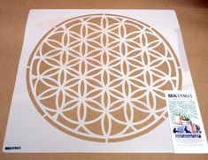 the cut out paper is laying on top of the cardboard box and it has a flower of life design