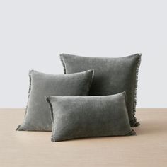 three grey pillows on a wooden table