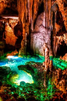 the inside of a cave filled with water and caves are lit up by green lights