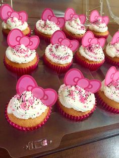 cupcakes decorated with pink and white frosting are arranged on a clear tray