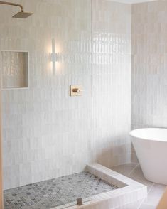 a white bath tub sitting next to a walk in shower under a bathroom light fixture