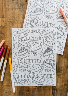 two coloring pages with crayons and markers next to them on a wooden surface