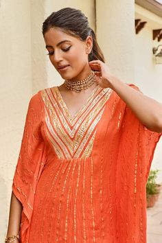 Orange flared sleeve kaftan with golden stripe pattern. Paired ivory lurex sharara.
Components: 2
Pattern: Stripe
Neckline: V Neck
Sleeve Type: Flared Sleeves
Fabric: Rayon Crepe Lurex
Color: Orange
Other Details: 
Kaftan:
Zari work yoke
Occasion: Sangeet - Aza Fashions Sharara For Women, Zari Work, Fashion App, Flared Sleeves, Aza Fashion, Sleeve Type, Color Orange, Stripes Pattern, Types Of Sleeves