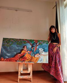 a woman standing next to a painting on a easel