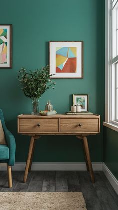 a living room with green walls and two framed pictures on the wall above a wooden table