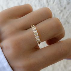 a woman's hand wearing a gold ring with small white stones on it,