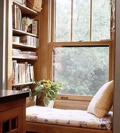 a window seat in front of a bookshelf filled with lots of books and flowers