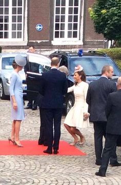 the couple are walking down the red carpet in front of some cars and two men