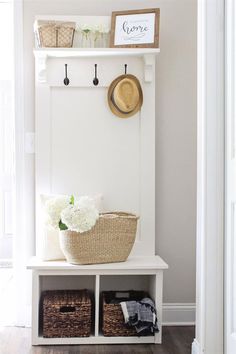 a white bench with baskets and flowers on it in front of a wall mounted coat rack