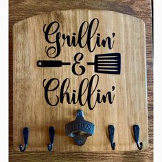 a wooden cutting board with the words grillin and chillin written on it, surrounded by kitchen utensils