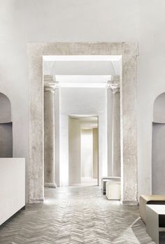 an empty hallway with white walls and columns