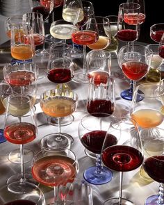 a table topped with lots of wine glasses filled with different types of wines and drinks