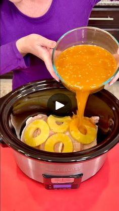 a woman pouring sauce into an slow cooker with onion rings on the side and carrots in the bowl