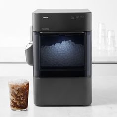 a blender sitting on top of a counter next to a cup filled with liquid