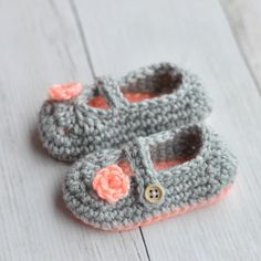 a pair of crocheted baby shoes sitting on top of a white wooden floor