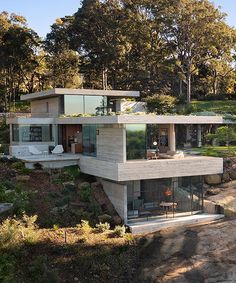 a modern house on top of a hill with trees in the background