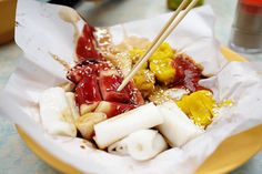 chopsticks sticking out of some food in a paper bowl on a table top