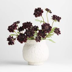 a white vase filled with purple flowers on top of a table