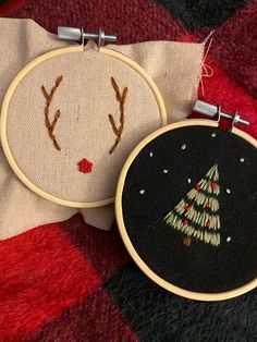 two hand embroidered christmas ornaments on a red and black checkered blanket