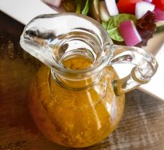 a glass jar filled with liquid sitting on top of a table next to a salad