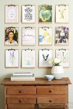 a wooden dresser sitting next to a wall with pictures on the wall and flowers in a vase