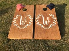 two wooden cornhole boards with the letters w and u painted on them, sitting in grass