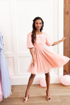 This soft pink knee-length dream dress has it all! From the bows, to the ruching and light-weight fabric, this feminine number is sure to become one of your favorite things. Inspired by Liesl Von Trapp in the Sound of Music. Available in size XXS-5X + matching mini sizes! Knee-length Dress With Gathered Neckline For Brunch, Spring Dresses With Gathered Waist And Knee-length, Spring Knee-length Dress With Gathered Waist, Feminine Spring Dress With Gathered Neckline, Spring Dresses With Pleated Bodice And Puff Sleeves, Elegant Pink Dress With Smocked Bodice, Feminine Knee-length Dress With Gathered Waist, Spring Party Midi Dress With Gathered Waist, Modest Ruched Dress For Spring