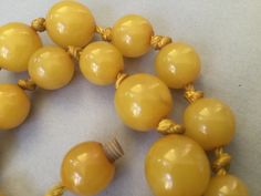 "Lovely egg yolk Bakelite single strand necklace. Hand tied graduated beads. Romantic, yellow necklace. Hidden bead clasp. Simply beautiful, gleaming, set of beads. Large knot, hand tied 1930s style. Chunky! Graduated beads: 8mm (smallest) to 17mm (largest) 15 1/2\" necklace Attention: All items are listed to the best of our observation, but they are pre-owned and pre-loved (meaning we may have missed something minor and/or be in need of light cleaning.) Please read our shop policies and/or conv Yellow Costume Jewelry Necklace For Formal Occasions, Yellow Costume Jewelry Necklace For Formal Events, Classic Yellow Round Bead Jewelry, Formal Yellow Jewelry With Round Beads, Vintage Polished Yellow Beads Jewelry, Vintage Yellow Single Strand Jewelry, Yellow Single Strand Beads For Jewelry Making, Vintage Yellow Jewelry With Polished Beads, Vintage Yellow Jewelry With Large Beads