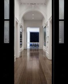 an empty hallway with wooden floors and white walls