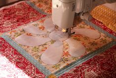 a sewing machine is sitting on top of a quilted tablecloth that has an orange and yellow flower design