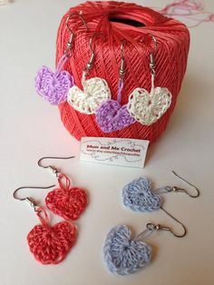 several crocheted hearts are on display in front of a red ball of yarn