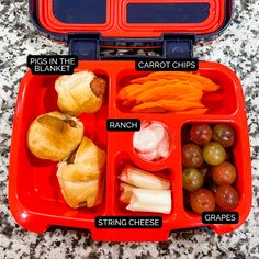 an open red lunch box filled with different types of vegetables and meats on it