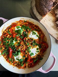 a pan filled with food sitting on top of a table next to bread and vegetables