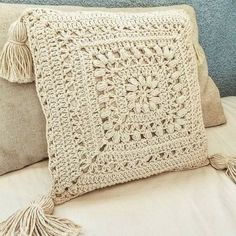 a crocheted pillow with tassels on it