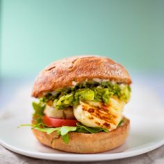 a sandwich with shrimp, lettuce and tomato on a white plate against a green background