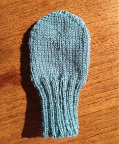 a knitted mitten sitting on top of a wooden table