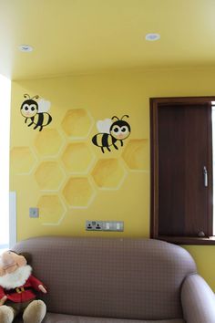 a stuffed animal sitting on top of a couch in front of a wall with bees