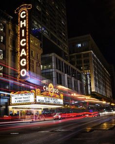 the chicago theater marquee is lit up at night with traffic passing by in the foreground