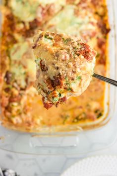 a close up of a spoon in a casserole dish with meat and cheese