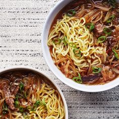 two bowls filled with noodles and meat on top of a table