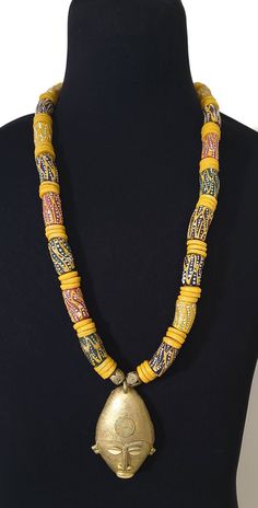 Make a statement in our bold Ghanaian bead necklace with an African mask pendant.  Beads are made from recycled glass and are also known as the Krobo Bead. Yellow Beaded Necklaces With Large Beads For Festivals, Yellow Beaded Necklace With Large Beads For Festivals, Large Yellow Beads For Festivals, Yellow Large Beads For Festivals, Artisan Yellow Beaded Necklaces For Festivals, Traditional Yellow Necklaces With Wooden Beads, Artisan Yellow Necklaces With Wooden Beads, Artisan Yellow Beads For Festivals, Artisan Yellow Necklace With Wooden Beads