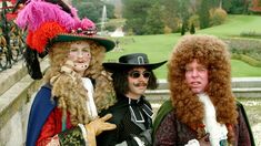 three people dressed up in costumes posing for a photo on a bridge over looking a park