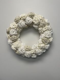 a white wreath made out of flowers on top of a gray wall with the word love written