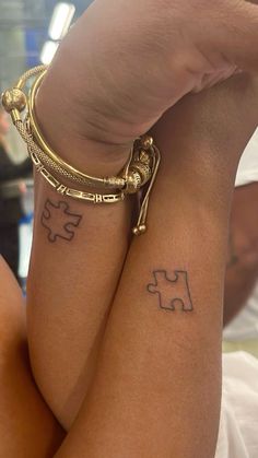 two people with matching tattoos on their arms and legs, one is holding the other's arm