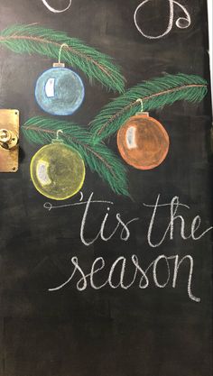 a chalkboard sign that says tis the season with ornaments hanging from it's branches