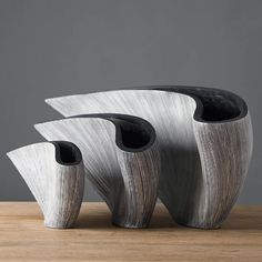 three black and white vases sitting on top of a wooden table