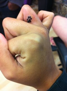 a person with a small dog paw tattoo on their thumb